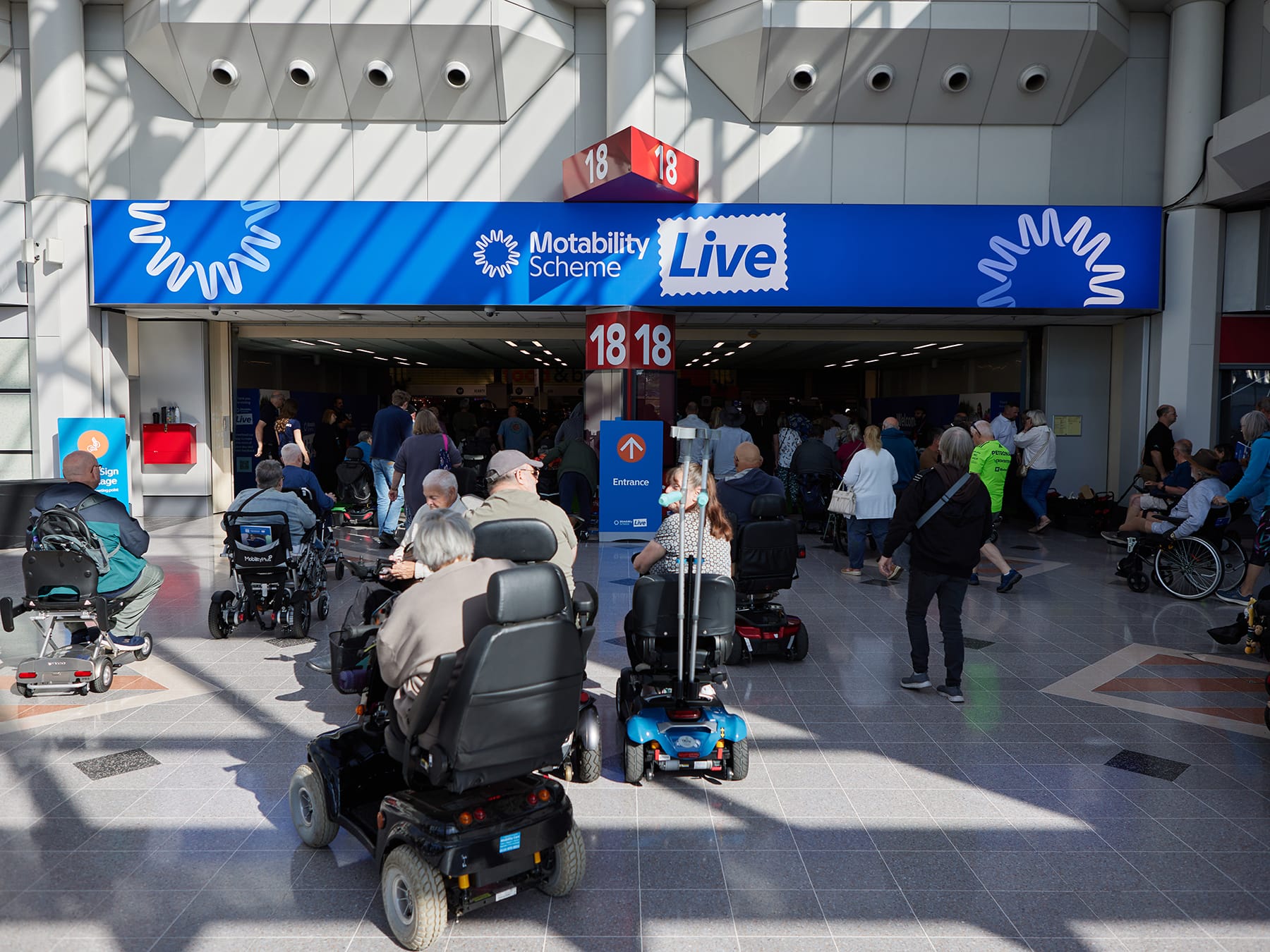 Visitors using mobility scooters and wheelchairs gather at the Motability Scheme Live event.