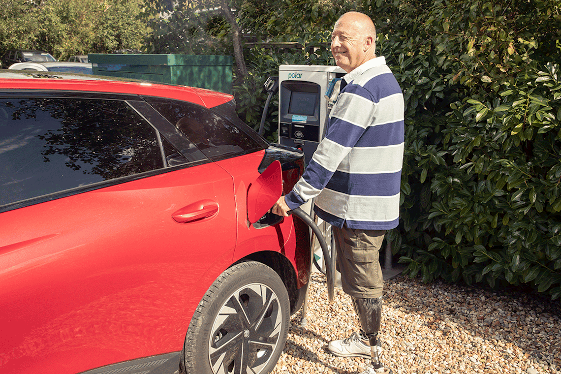 A man charging red electric car