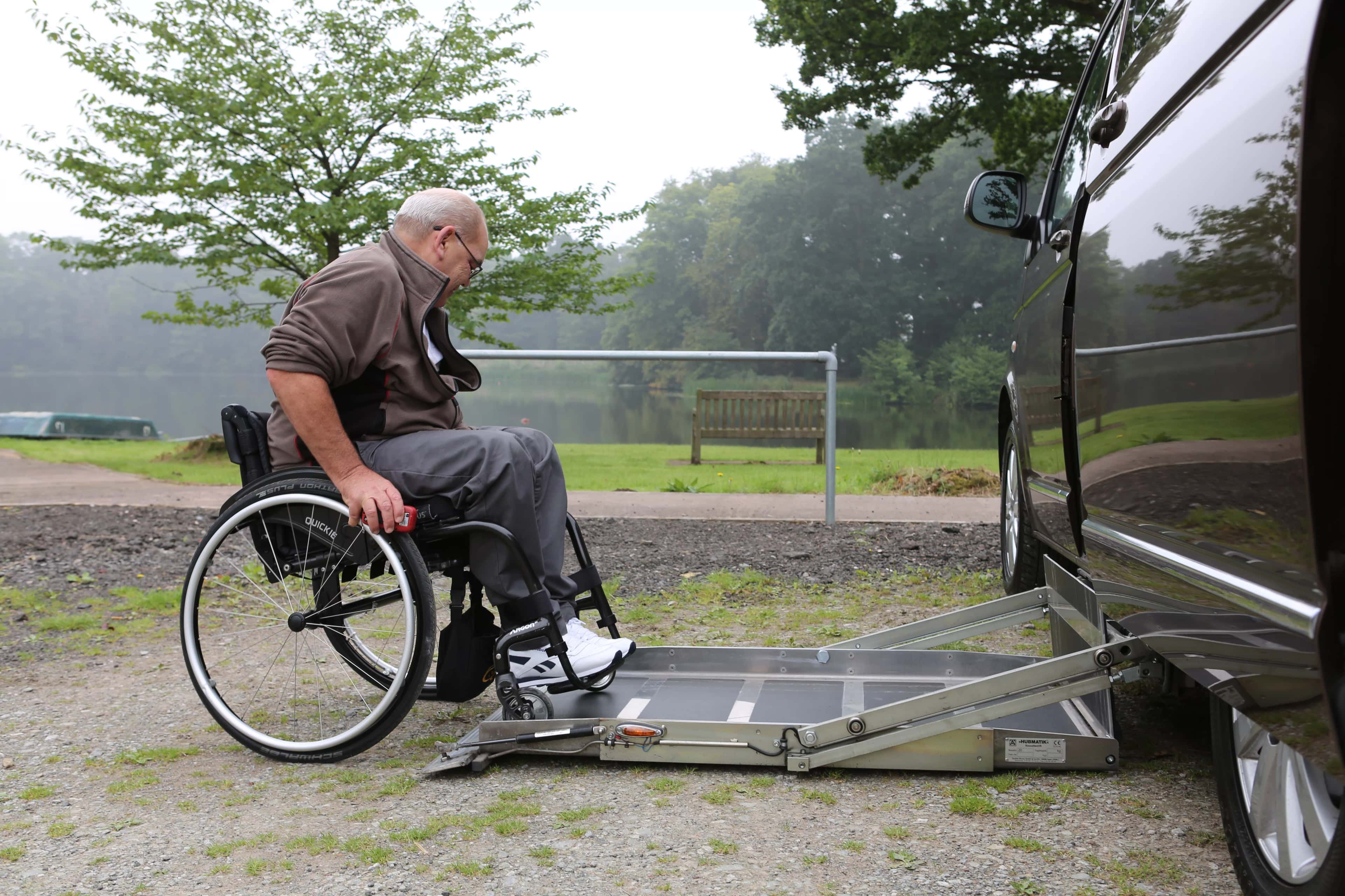A man in a wheelchair using a lift to get into a WAV