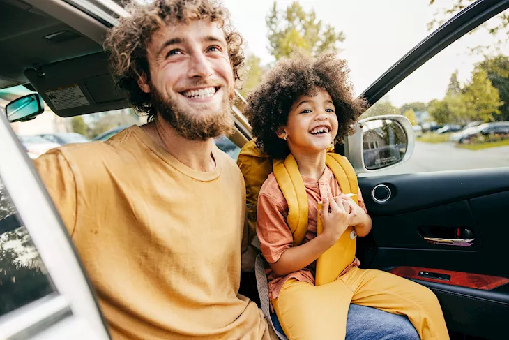 Man and child sitting happily in a Motability vehicle