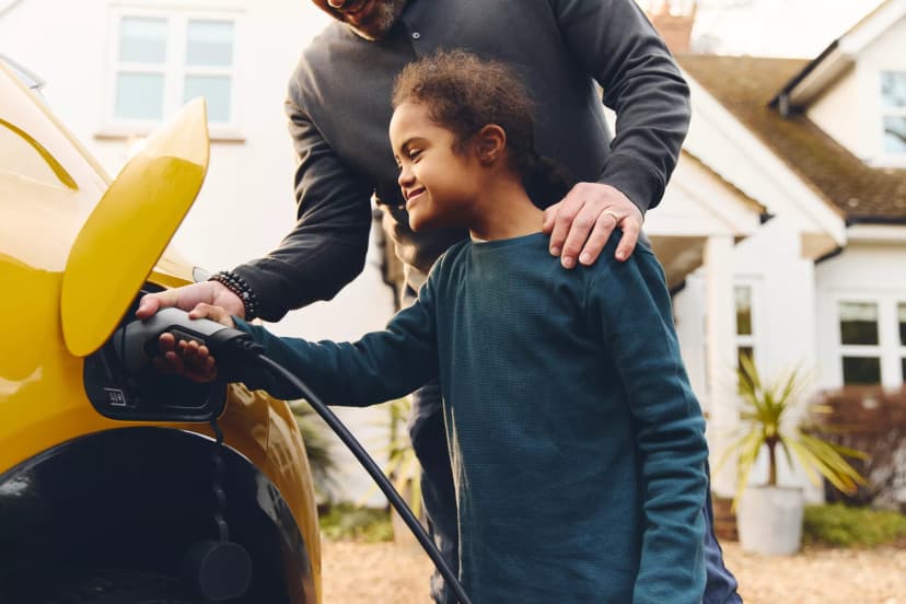 child and father charging their electric car