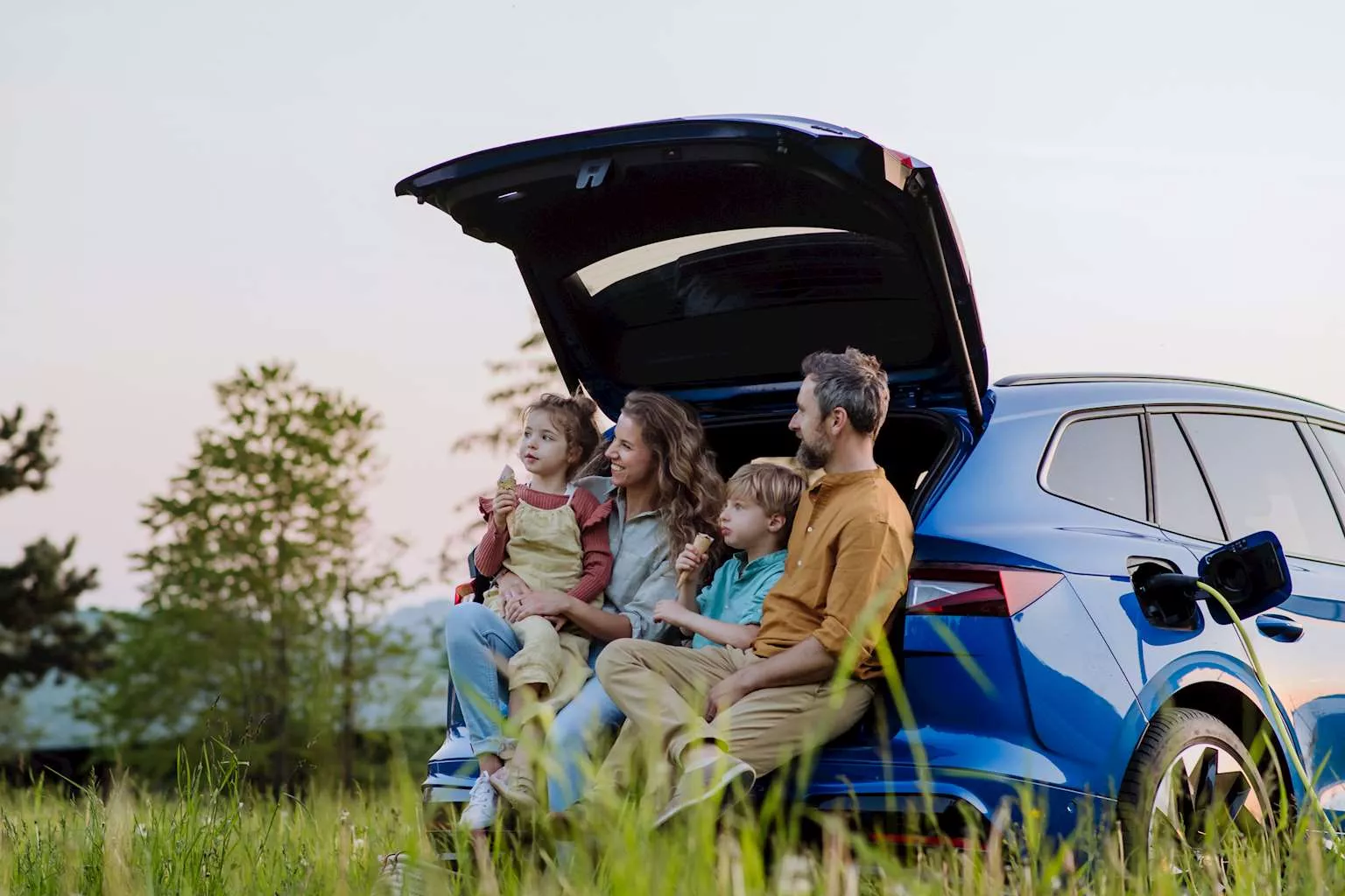 family of four sitting in their electric car boot
