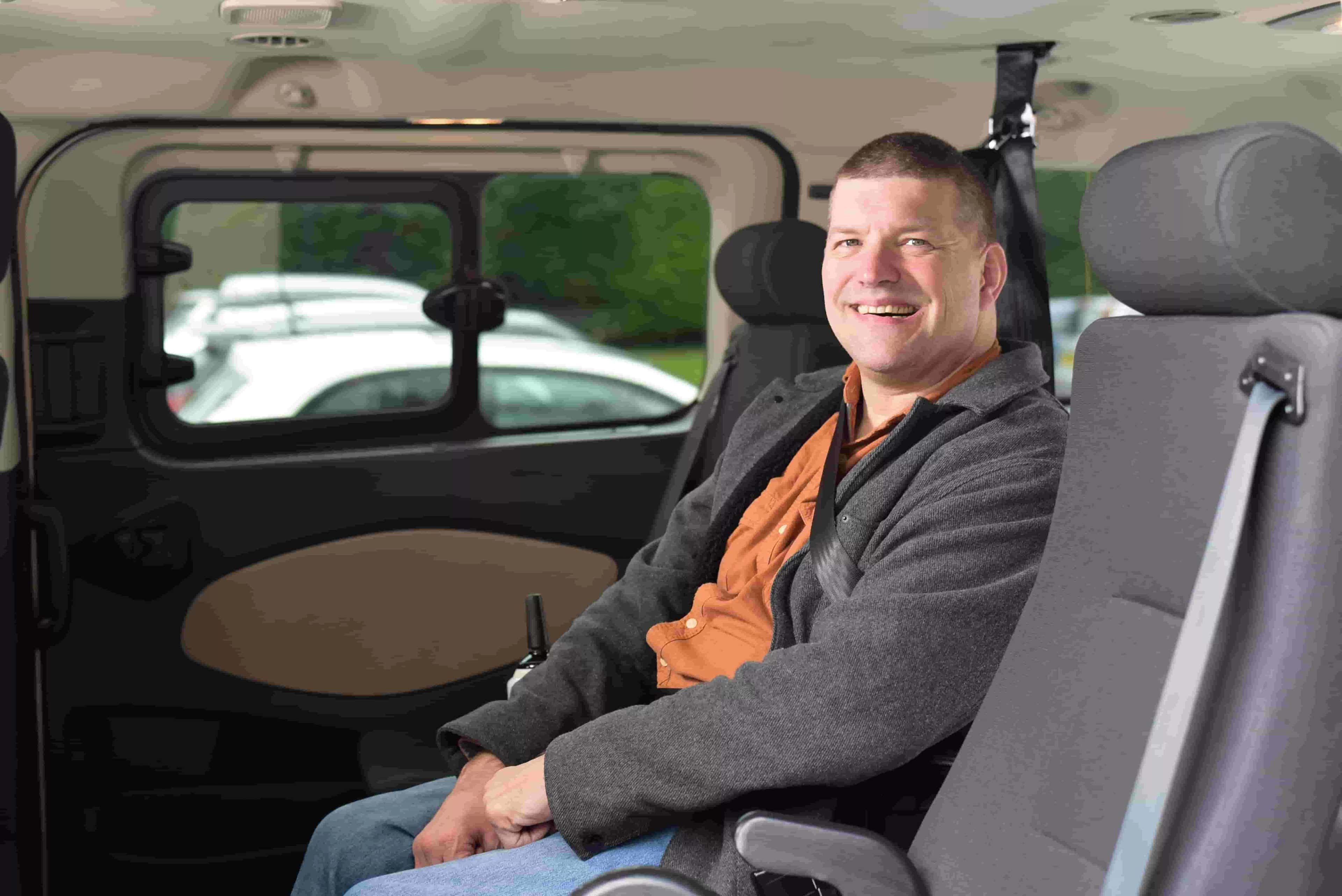 A woman smiling in a wheelchair, inside a WAV