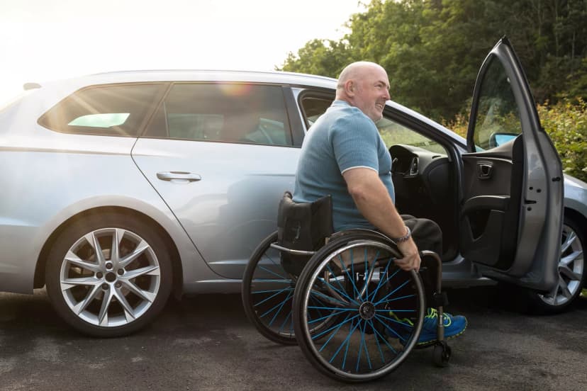 man in a wheelchair getting into his car